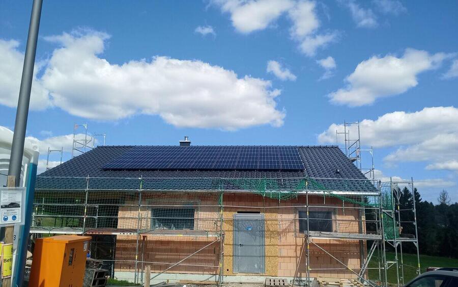 Neubau mit Baugerüst, das Satteldach ist bereits vollflächig mit Solarmodulen belegt