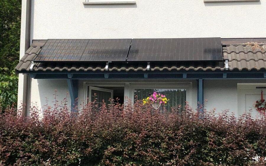Vier Solarmodule flach auf dem Ziegel-Vordach einer überdachten Terrasse