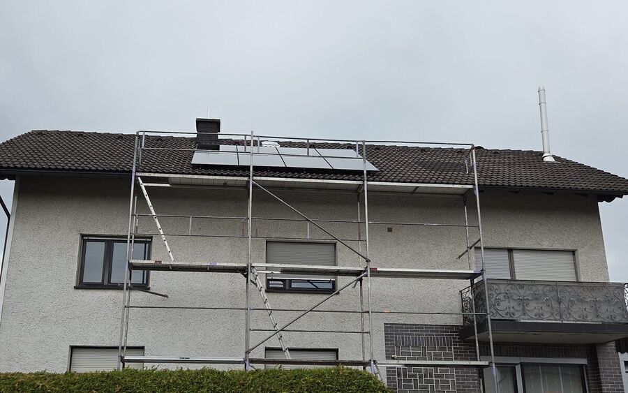 Vier Solarmodule dicht unter dem First eines Wohnhauses in Buchbach, davor steht noch das Gerüst