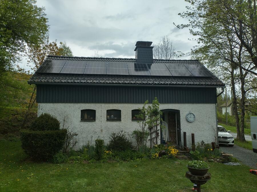 Solarmodule über die ganze Länge des Satteldachs eines weiß verputzten Gebäudes mit dunkel verschaltem Obergeschoss bei Förtschendorf im Frankenwald