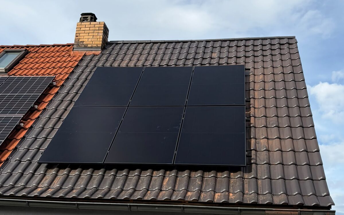 Sechs schwarze Solarmodule auf einem braunen Ziegeldach in Kronach, links daneben eine ältere Anlage auf rotem Ziegel