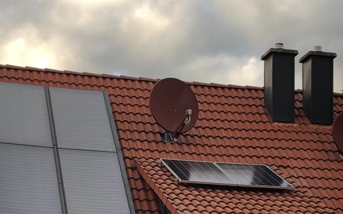 Ziegeldach mit hellen Solarthermie-Kollektoren links und einem Photovoltaikmodul auf der Gaube