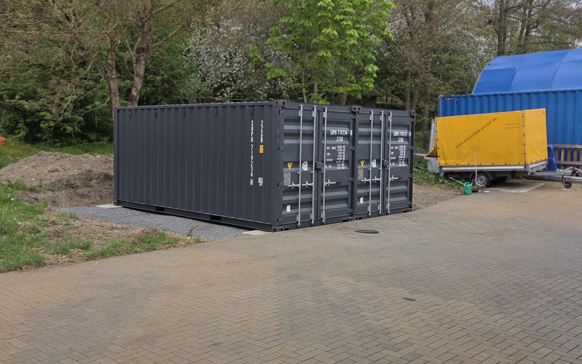 Dunkelgrauer Seecontainer als Lagerraum auf einer gepflasterten Fläche